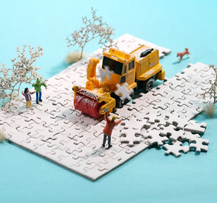 A miniature calendar work by Tatsuya Tanaka with a snowplow on a puzzle piece road, clearing snow.