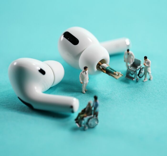 A miniature calendar work by Tatsuya Tanaka, illustrating tiny doctors and patients around oversized wireless earbuds.