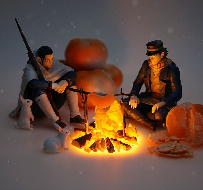Miniature calendar works by Tatsuya Tanaka: Two figures warming themselves by a campfire made of tangerine peels.