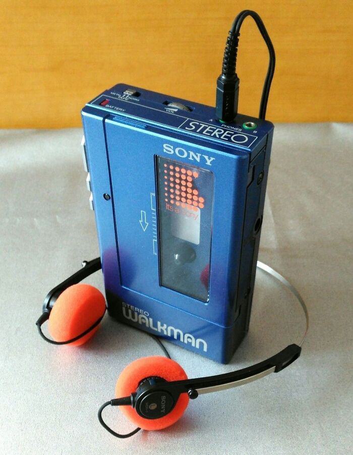 Retro tech photo capturing an 80s blue Sony Walkman with orange headphones.