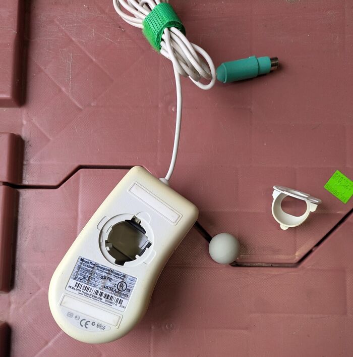 An upside-down vintage computer mouse with the trackball removed, showcasing retro tech from the 80s.