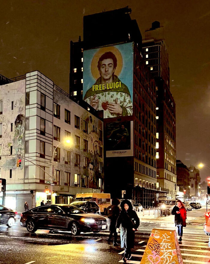A large outdoor banner featuring a stylized portrait with 'FREE LUIGI' text, part of 'Eat The Rich' moments.