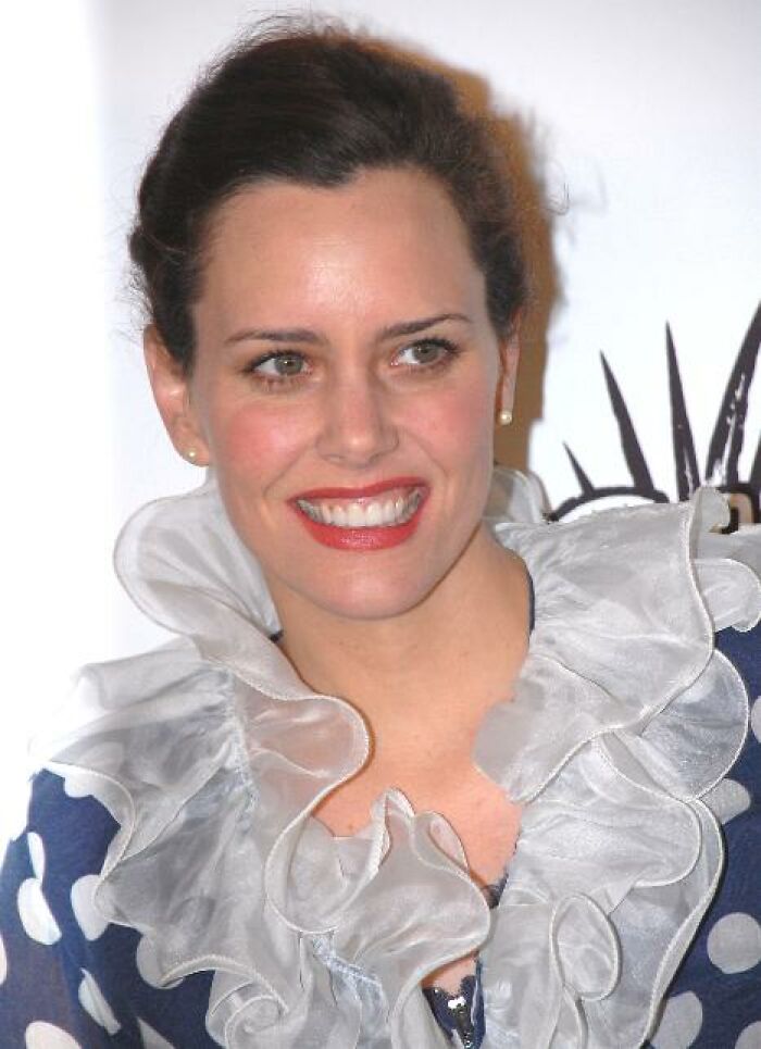 Ione Skye, with her career highlights, smiles brightly, showcasing a ruffled white collar over a blue polka-dot dress.