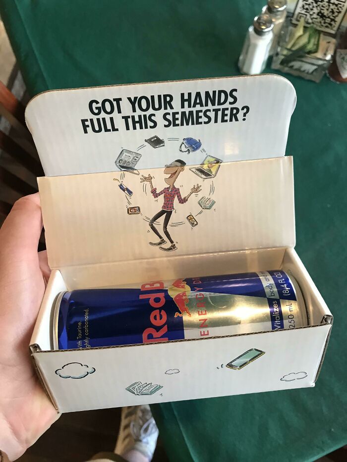 An open box containing two Red Bull cans, promoting energy for a horrid and sad world.