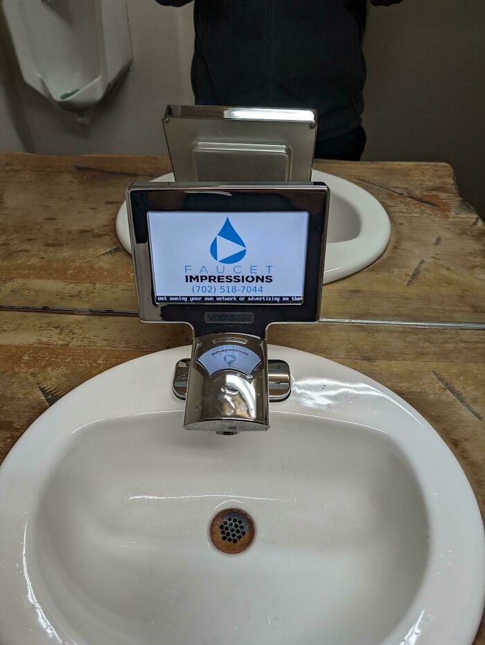 A faucet with a screen showing an advertisement, highlighting the horrid and sad world.