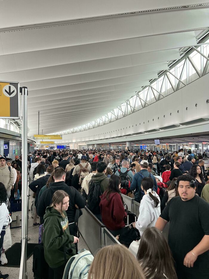 A massive crowd of people waiting in a long line at an airport, depicting the horrid and sad world.