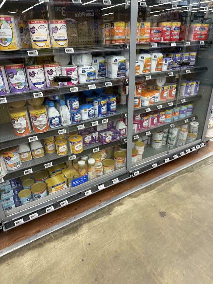Baby formula locked behind a glass case in a store, a reflection of the horrid and sad world.