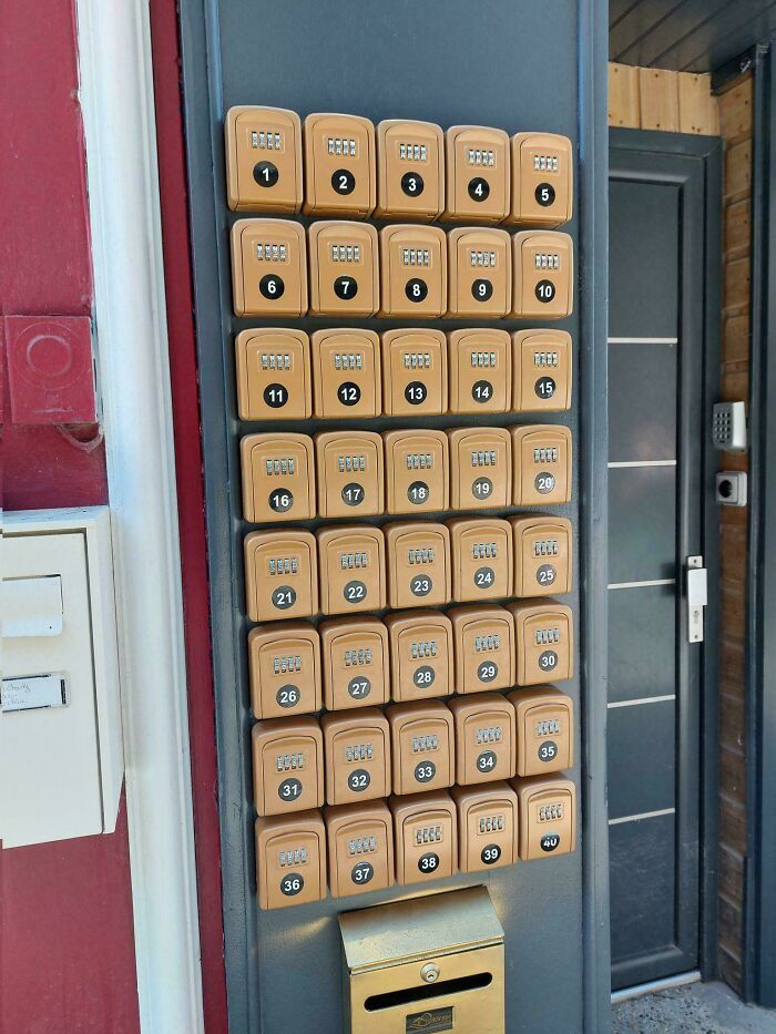 A wall with 39 small lockboxes and a larger mailbox below, depicting a horrid world.