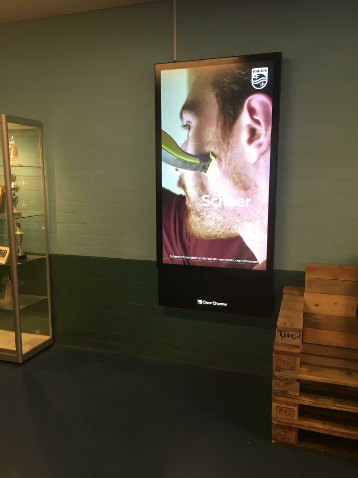 A digital display on a teal wall showing an advertisement for Philips shaver, highlighting a horrid world problem.