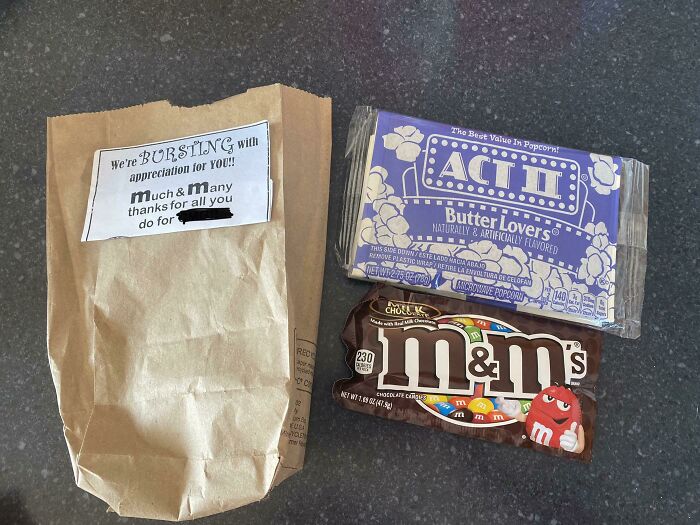 A brown paper bag with a thank you note, alongside Act II popcorn and M&M's, a sad world scene.