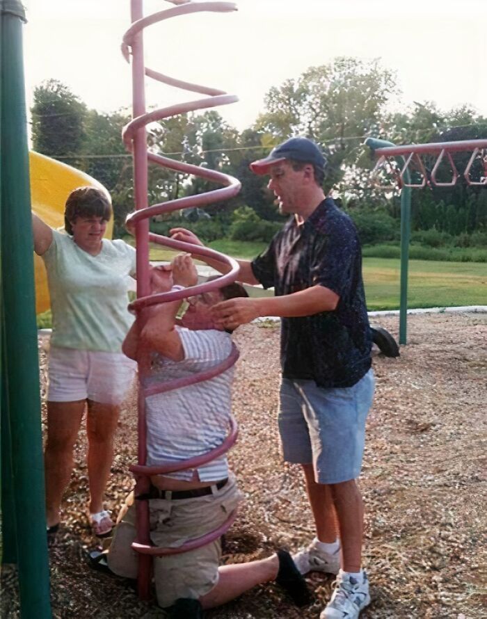 Three people on a playground, with one man humorously trapped inside a red spiral slide, providing crazier evidence.
