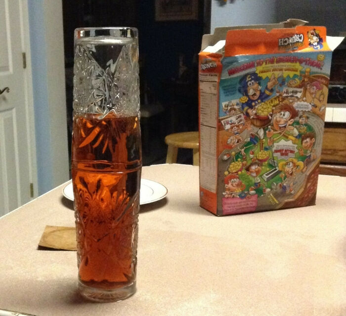 A tall glass filled with liquid and an inverted glass on top, a baffling image next to a cereal box that makes no physical sense.