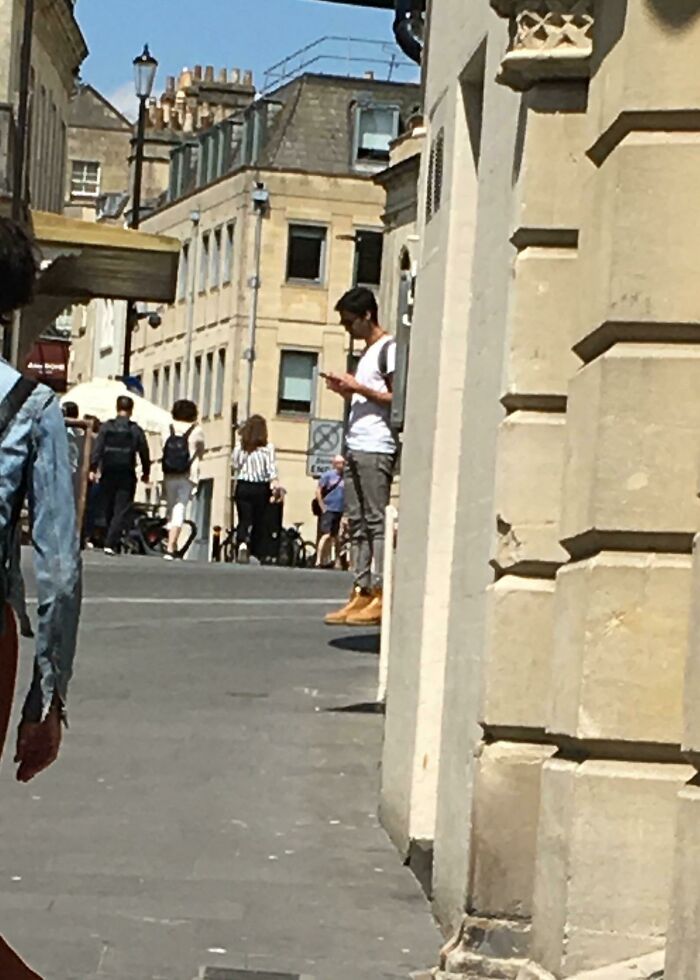 A baffling image of a man appearing to levitate against a building on a city street.