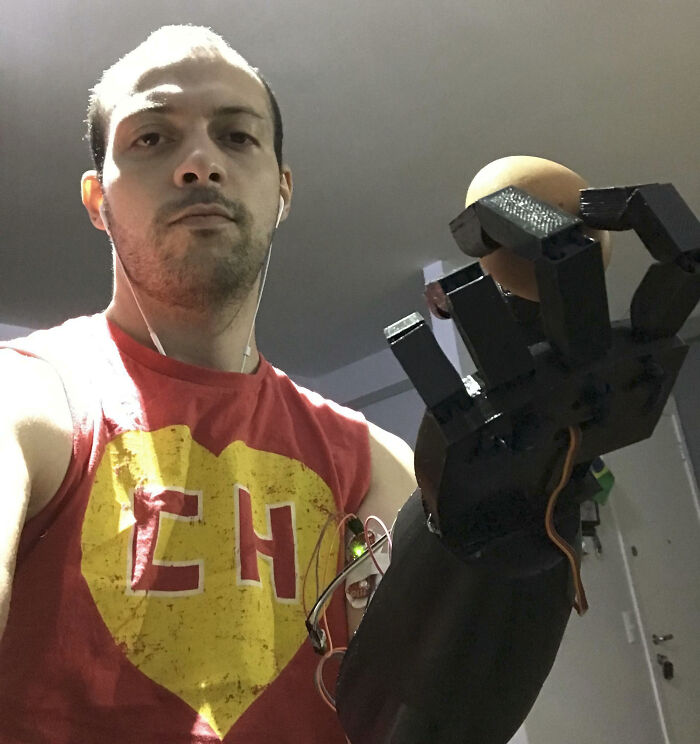 A man holding a black 3D printed prosthetic hand, displaying brilliant creations from 3D printers.