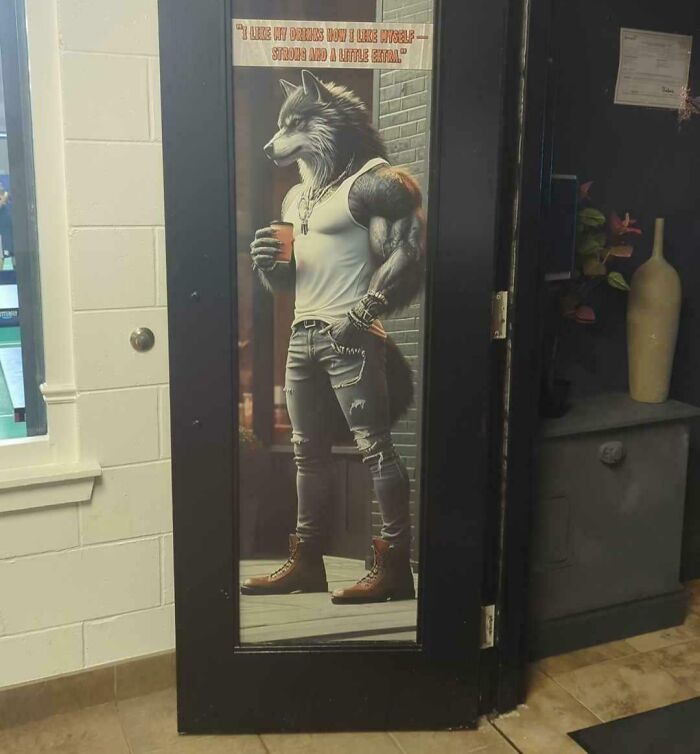 A cringey life-sized door sticker of a muscular wolf-man drinking from a cup, wearing jeans and a tank top.