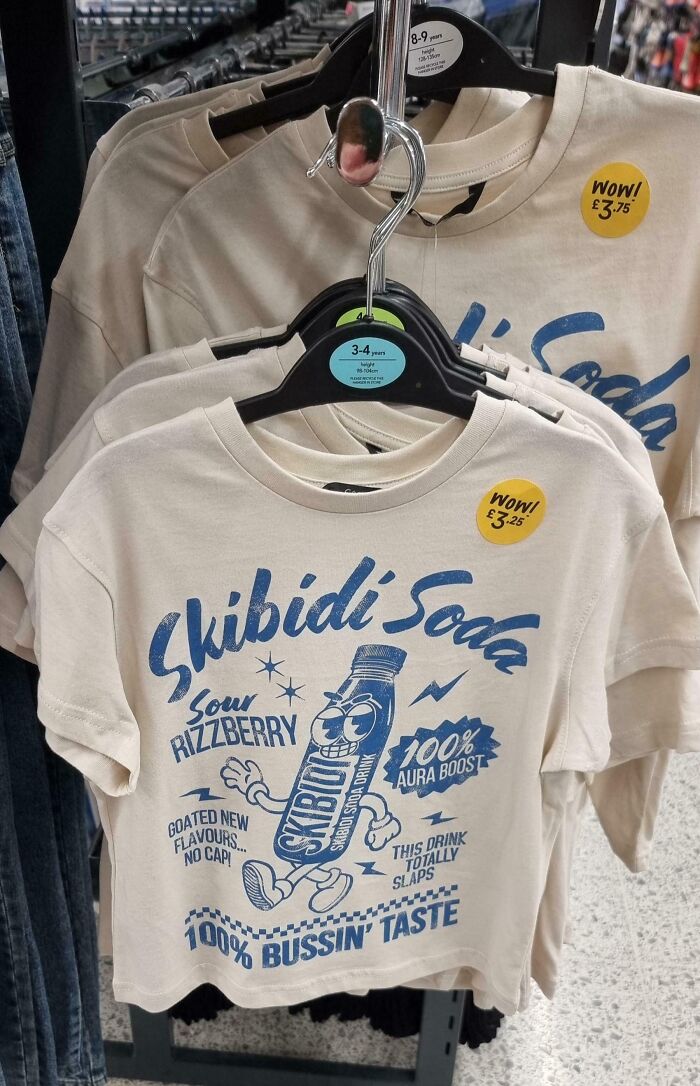 A cringey t-shirt with Skibidi Soda branding, featuring a cartoon soda bottle and phrases like 100% Aura Boost.
