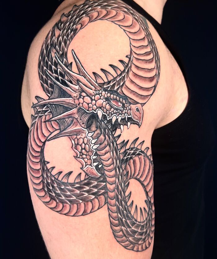 A stunning mythology inspired tattoo of a coiled dragon, an impressive art from Sacred Gold Studio.