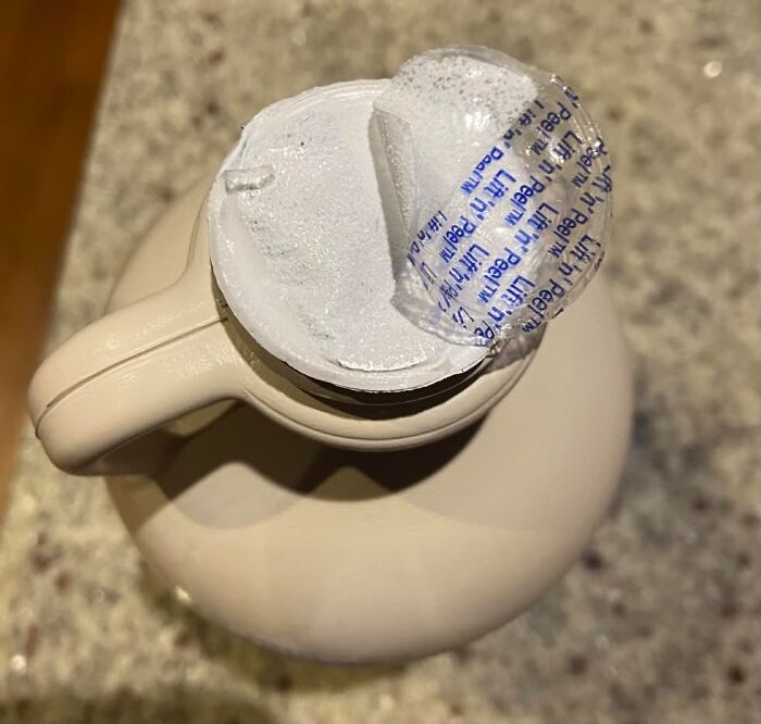 A partially peeled tamper-evident seal on a bottle, a funny description of everyday inconveniences.