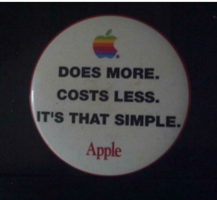 A vintage Apple pin button with the logo and the text: DOES MORE. COSTS LESS. IT'S THAT SIMPLE. Apple. The image shows how beliefs and words age over time.