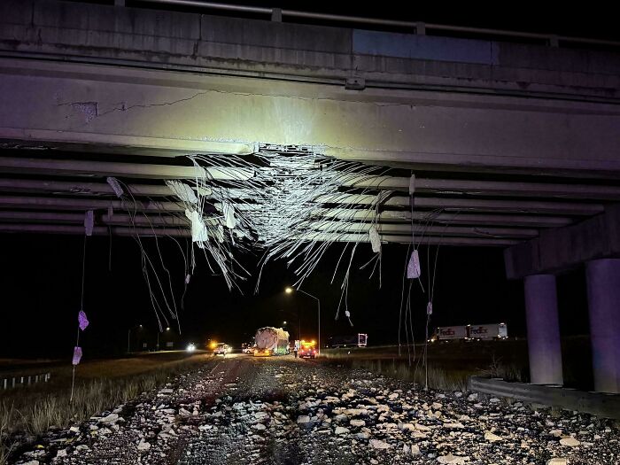 A truly bizarre image of a damaged highway overpass at night with exposed rebar, suggesting one might be hallucinating.