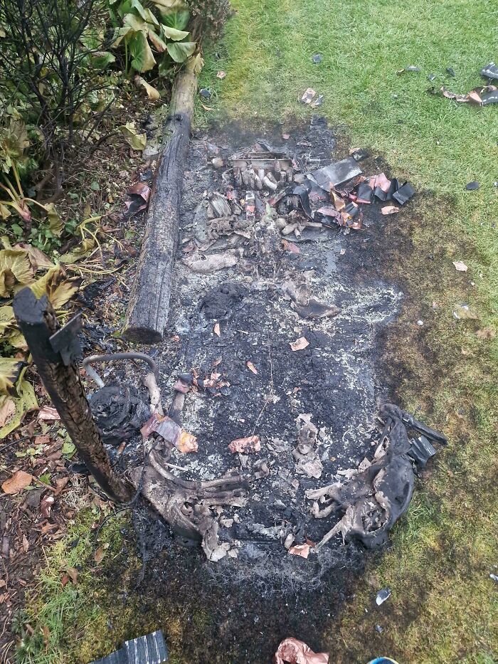 A truly bizarre sight of a burnt motorcycle frame and debris on green grass, making one wonder if they're hallucinating.
