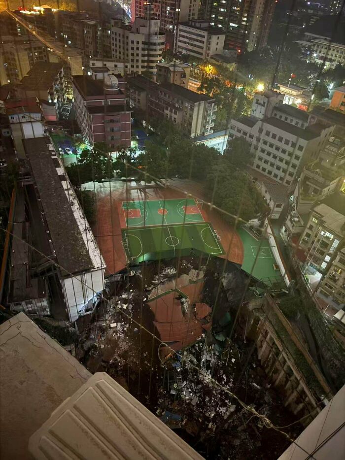 Truly bizarre sinkhole next to a building and sports courts, showing things people had to take a photo of.