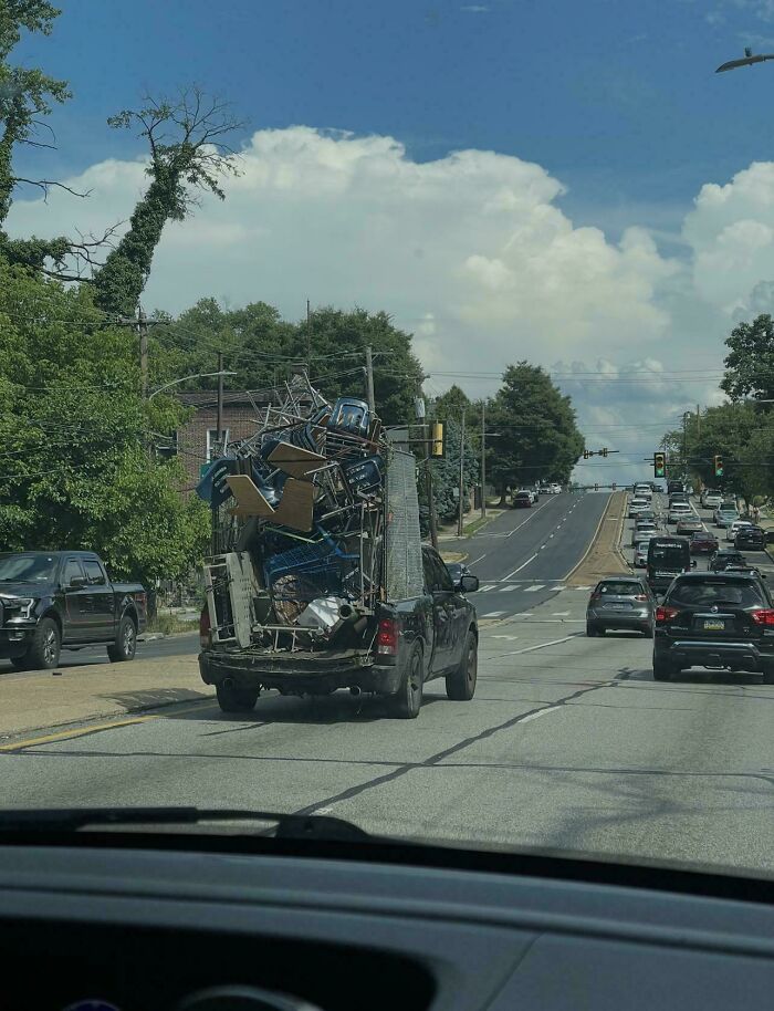 A truly bizarre and dangerously overloaded truck carrying scrap metal on a highway.