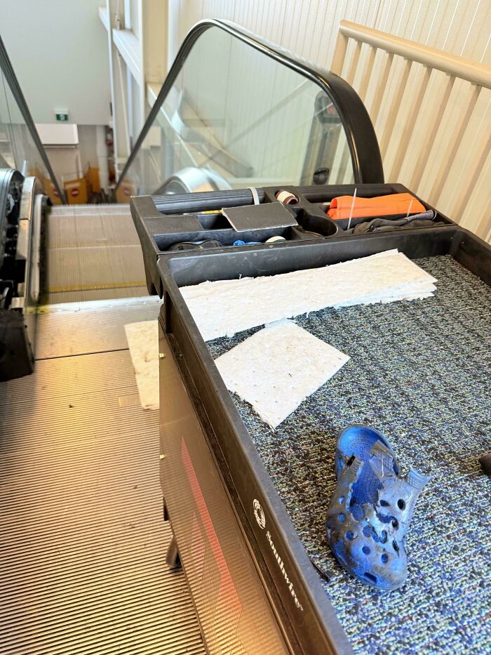 A truly bizarre scene on an escalator with a blue shoe and cleaning supplies.