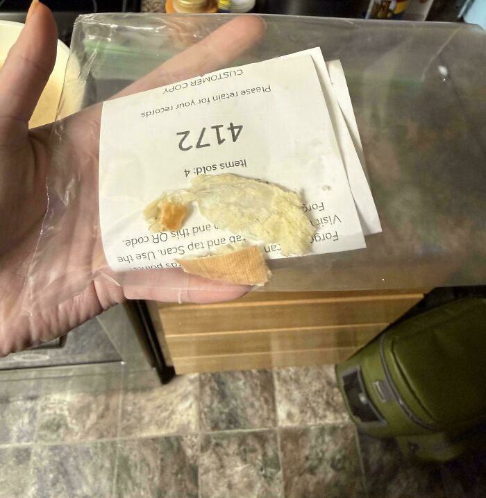 A person holding a receipt with a used bandage stuck to it, a truly bizarre thing to take a photo of.