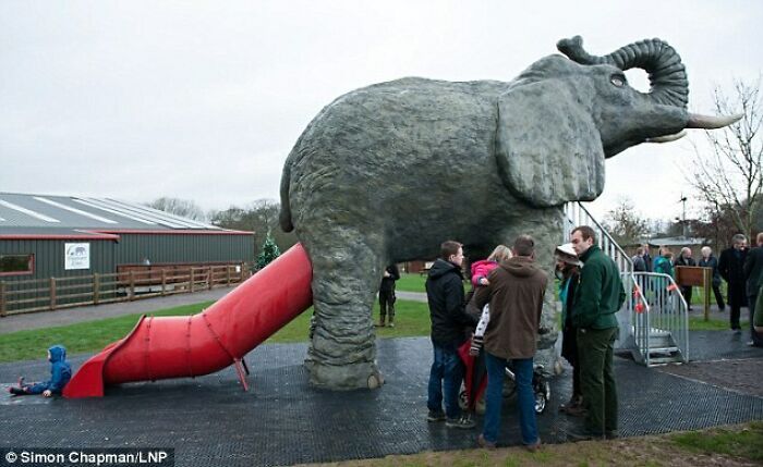 An enormous grey elephant statue with a red slide coming out of its rear, illustrating funny playground fails.