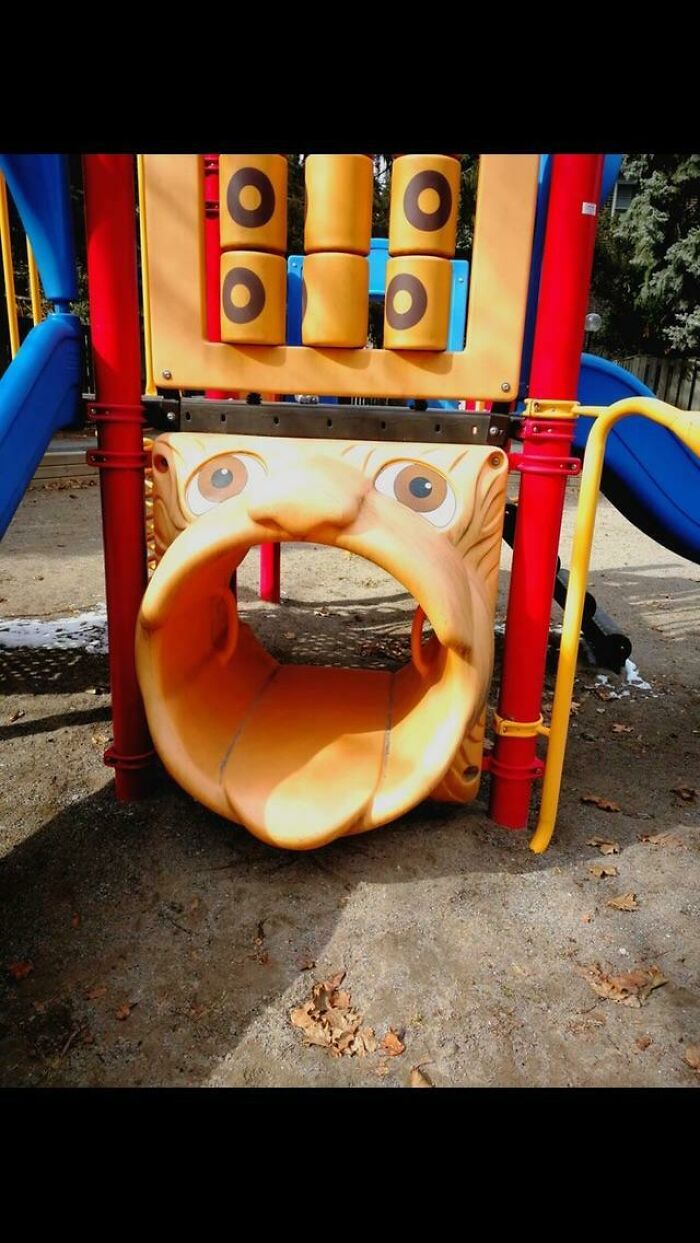 A playground slide shaped like a giant orange face with a wide-open mouth, a prime example of playground fails.