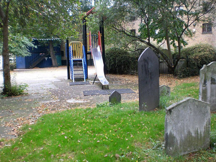 A playground with a slide next to a graveyard, an example of a playground fail.