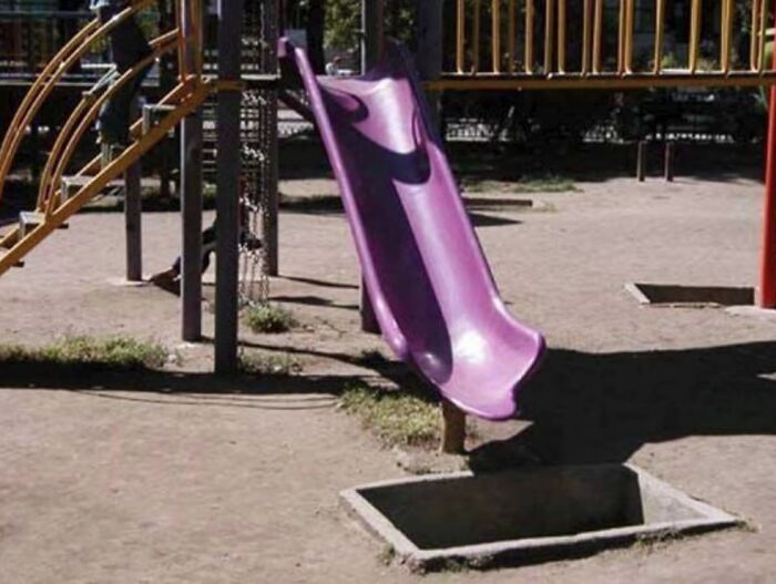 A purple playground slide ends abruptly into a square hole in the ground. This playground fail looks designed by someone who hates children.