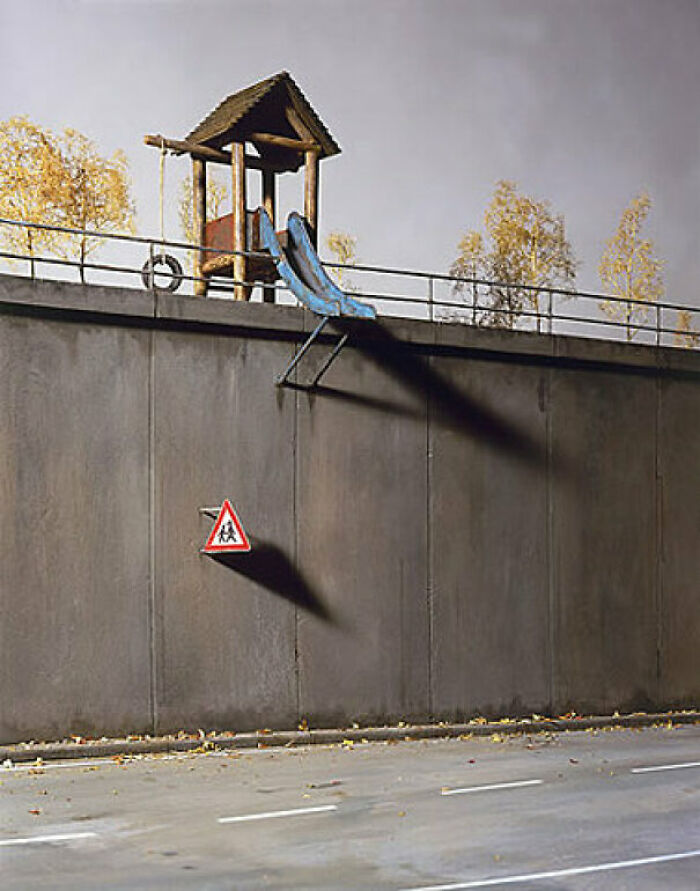 A playground with a slide going over a high wall and a children crossing sign. This playground fail looks designed by someone who hates children.