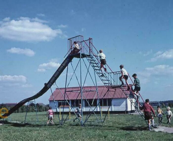 Kids climbing a dangerously tall, old-fashioned playground slide, a clear example of playground fails.
