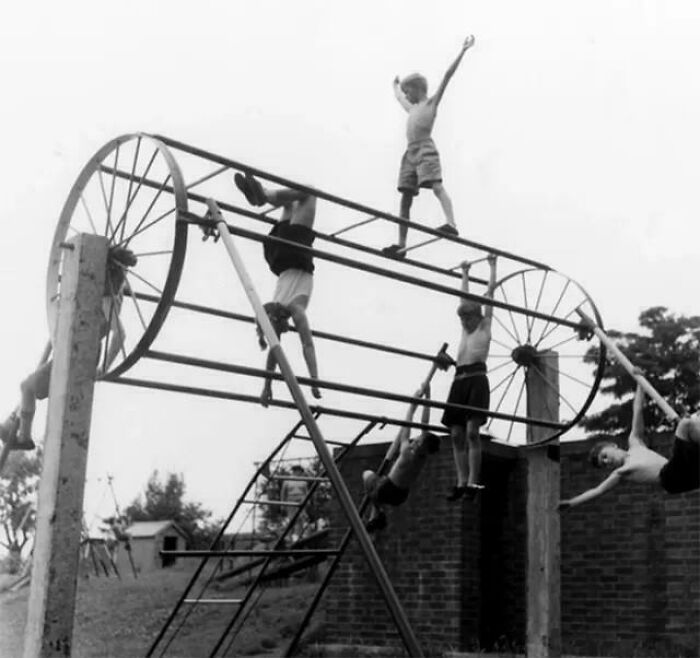 Children playing on a vintage, wheel-shaped climbing structure, demonstrating a past playground fail design.