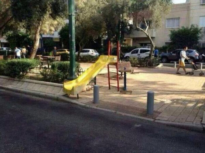 A playground slide ending abruptly at a sidewalk, a design fail in playground safety.