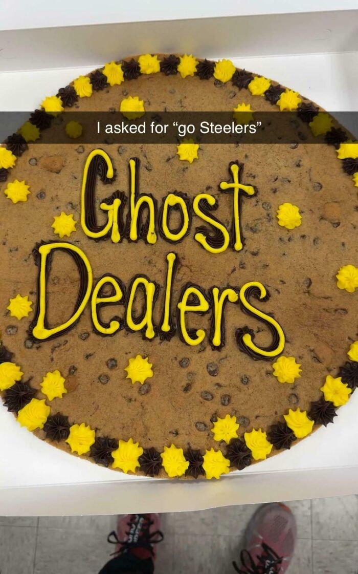 A large cookie cake with a misspelling 'Ghost Dealers' instead of 'Go Steelers,' highlighting a baker's amazing treat.