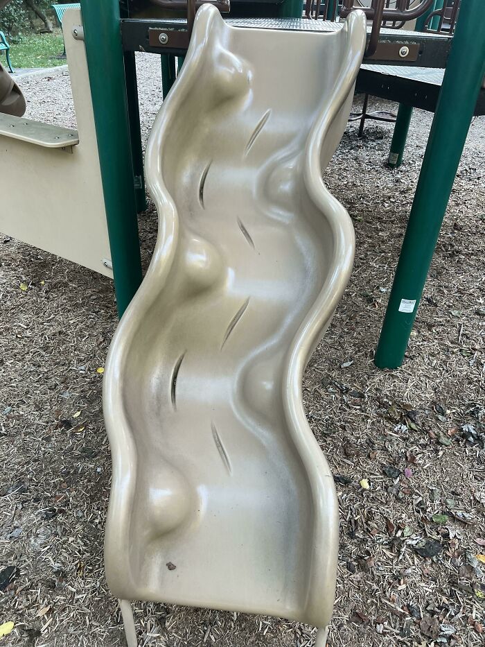 A bumpy, damaged playground slide with several large cracks, a clear example of a playground fail.