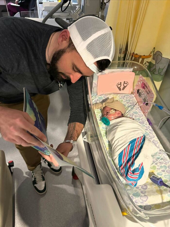 A caring man reads to a newborn baby in an incubator, proof he's the right man.