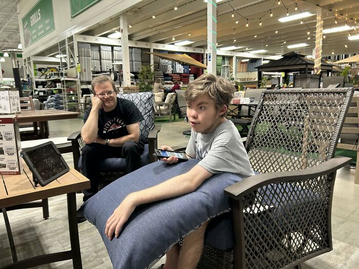 Two men sitting in outdoor furniture in a store, proving they found the right man after 40 years together.