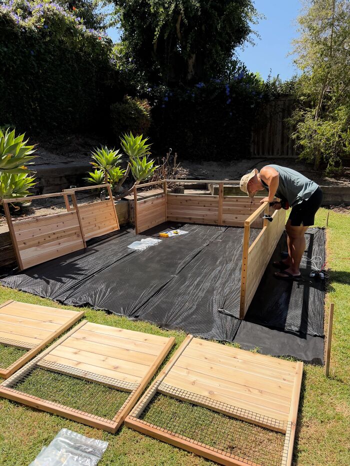 A man building a wooden structure in a garden, proving he is the right man for the job.