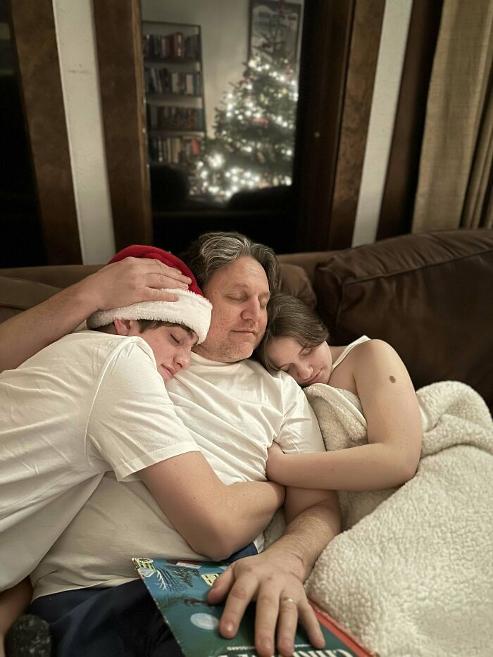 A father and two children cuddle on a couch with a Christmas tree in the background. Proof of finding the right man.