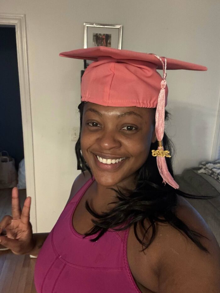 A woman wearing a pink graduation cap smiles, showing proof she found the right man.