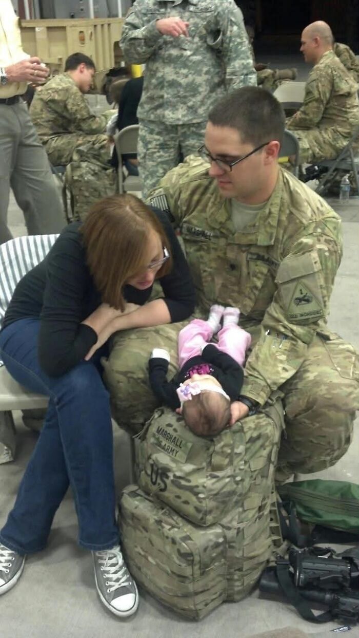 A woman and a soldier in uniform look at their baby, proof of finding the right man, on the soldier's lap.