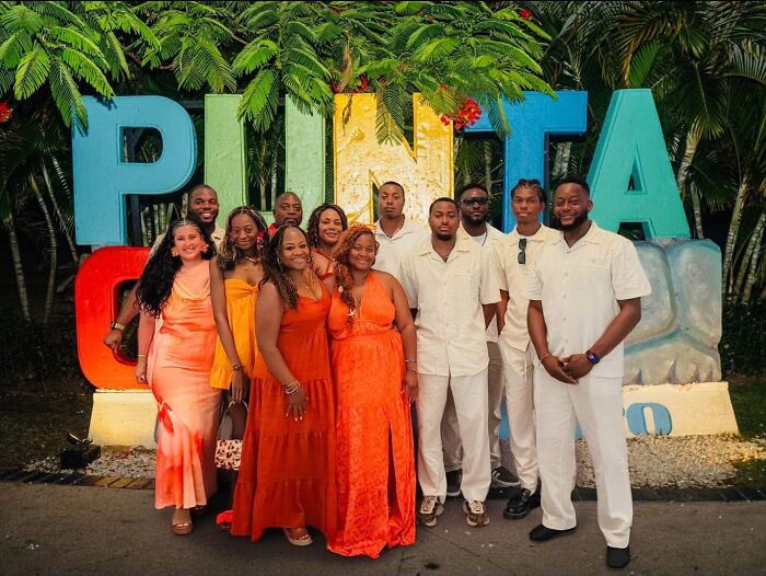 A group of women and men posing in front of a colorful Punta Cana sign. Proof of finding the right man.