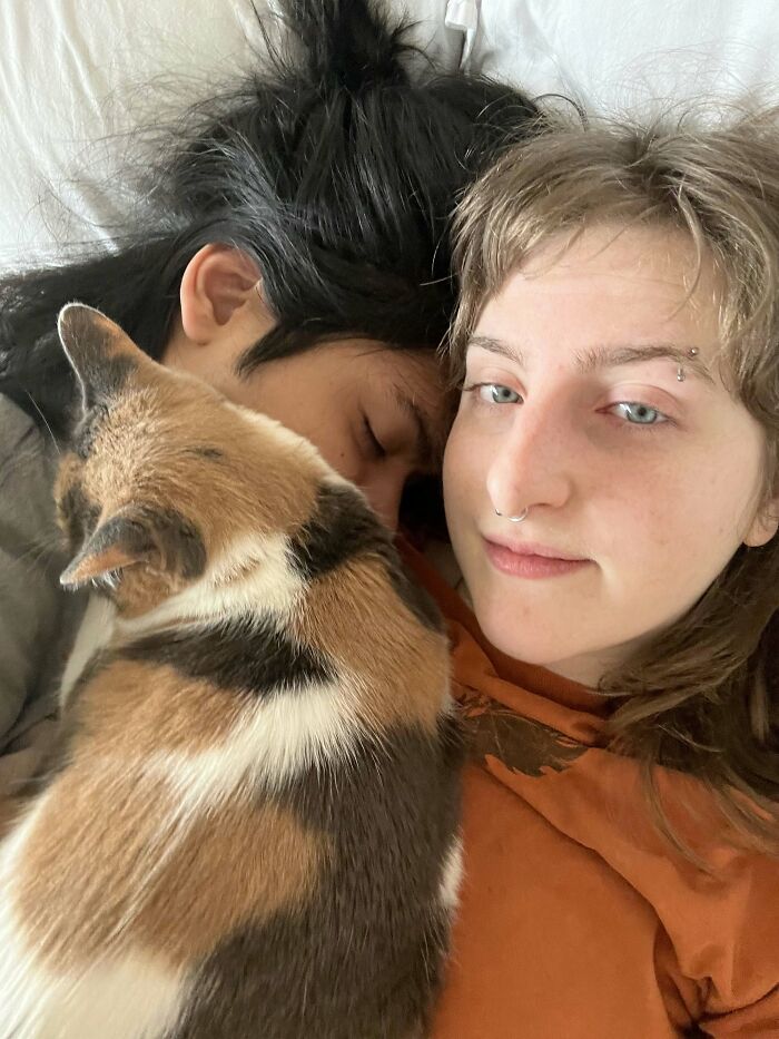 A woman and a man sleeping together with a cat, showing sweet proof of finding the right man.