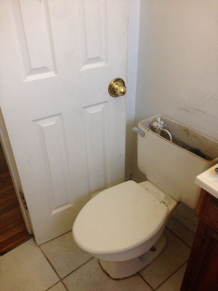 A toilet installed too close to a door, preventing it from opening fully, showing questionable home improvement.