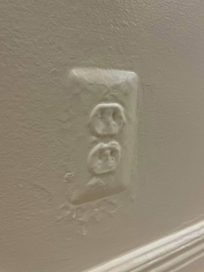 Questionable results from a home improvement project: a painted-over electrical outlet on a wall.