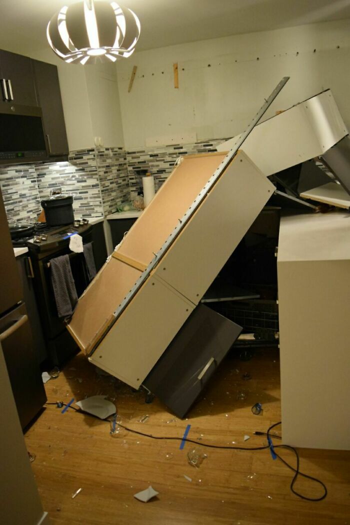 Questionable home improvement project: fallen kitchen cabinets scattered on the floor after a renovation gone wrong.